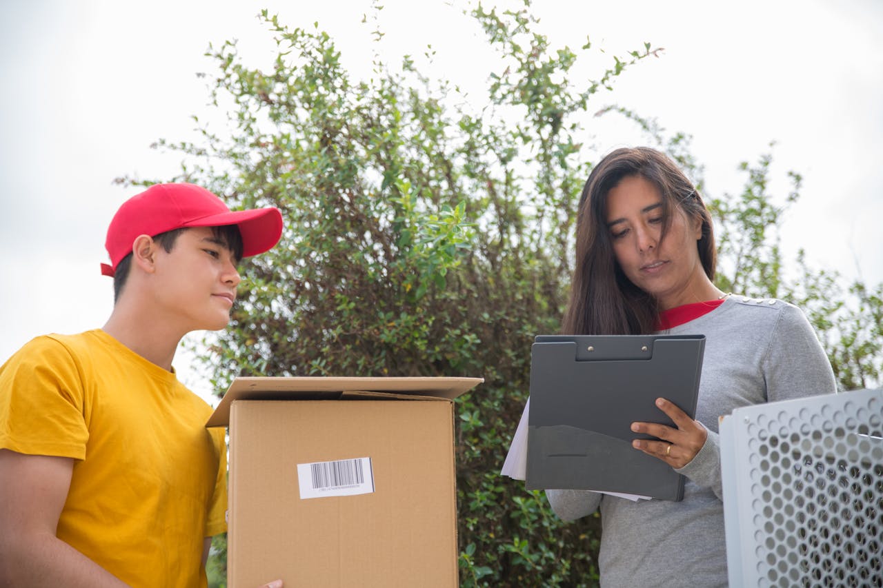 about-us Courier delivering a package while a woman signs a form outdoors.